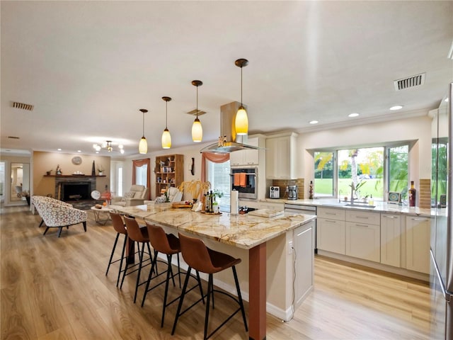 kitchen with visible vents, a kitchen island, light stone countertops, appliances with stainless steel finishes, and a fireplace