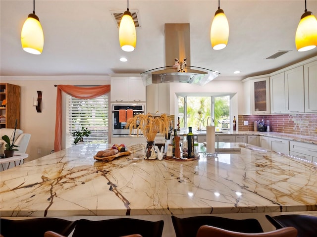 kitchen featuring decorative backsplash, island exhaust hood, visible vents, and oven