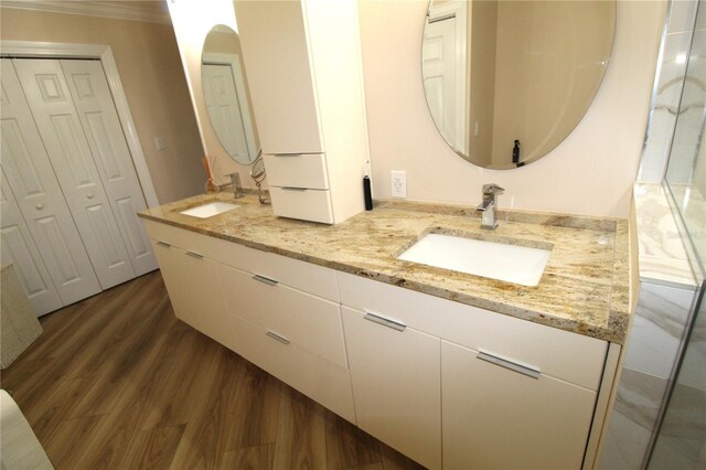 full bathroom featuring a sink, wood finished floors, double vanity, and crown molding