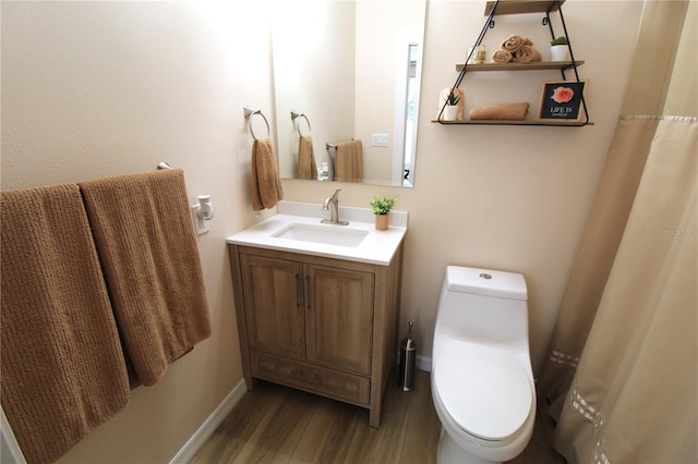 bathroom with vanity, toilet, wood finished floors, and baseboards