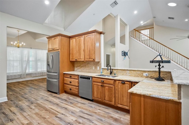 kitchen featuring light stone counters, brown cabinets, stainless steel appliances, visible vents, and a sink