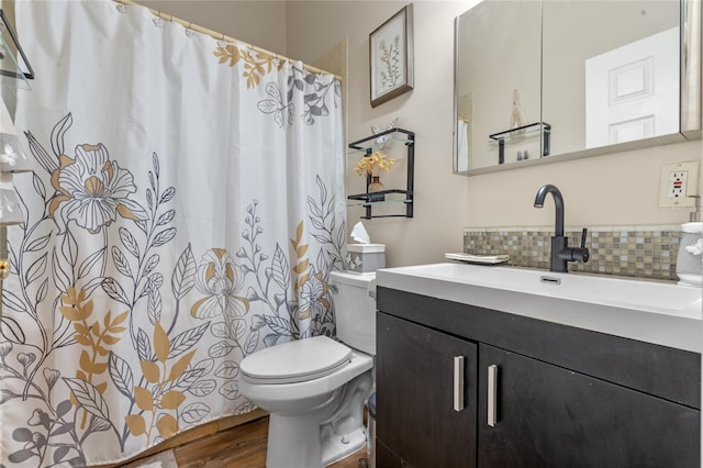 bathroom with toilet, wood finished floors, backsplash, and vanity