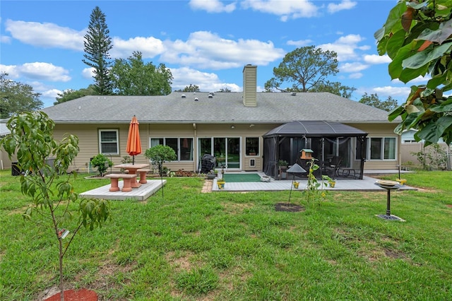 rear view of property with a yard, a shingled roof, a lanai, a chimney, and a patio area