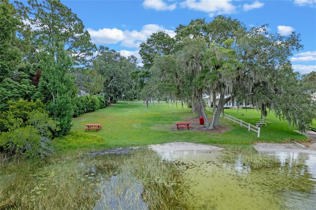 surrounding community with a water view and a lawn