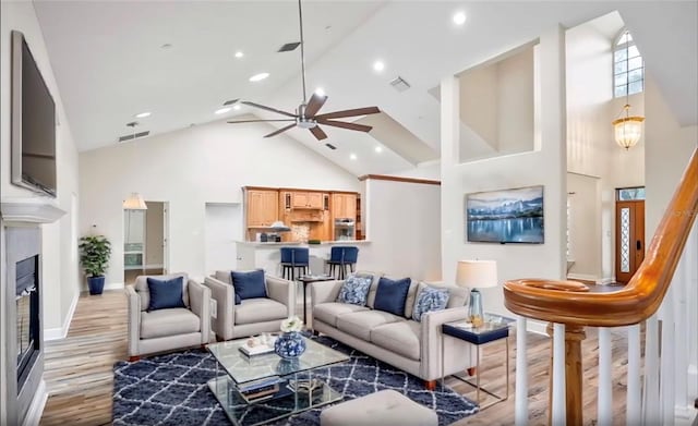 living area with light wood-style floors, ceiling fan, visible vents, and high vaulted ceiling