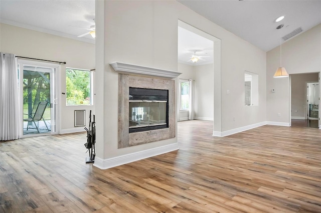 unfurnished living room featuring visible vents, baseboards, ceiling fan, a multi sided fireplace, and wood finished floors