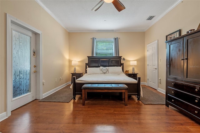 bedroom with visible vents, a textured ceiling, crown molding, and wood finished floors