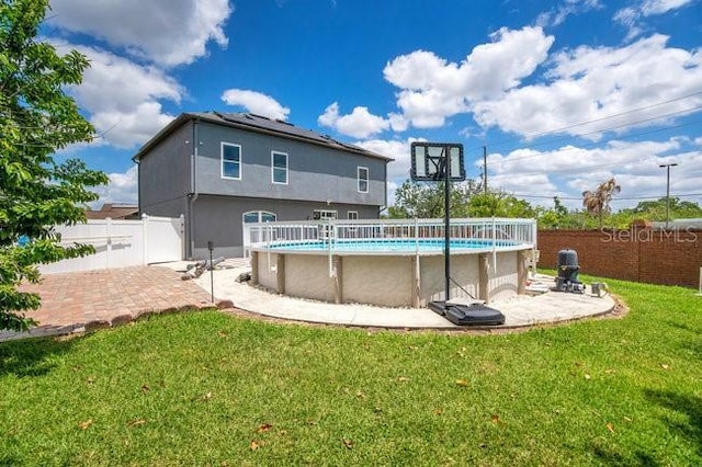 rear view of house featuring a fenced in pool and a yard