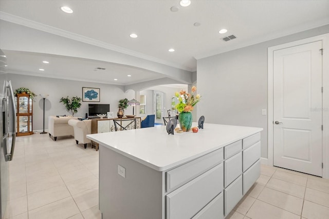 kitchen featuring stainless steel fridge, light tile patterned floors, a center island, and crown molding