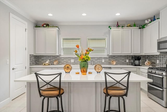 kitchen featuring a breakfast bar, a center island, stainless steel appliances, and white cabinetry