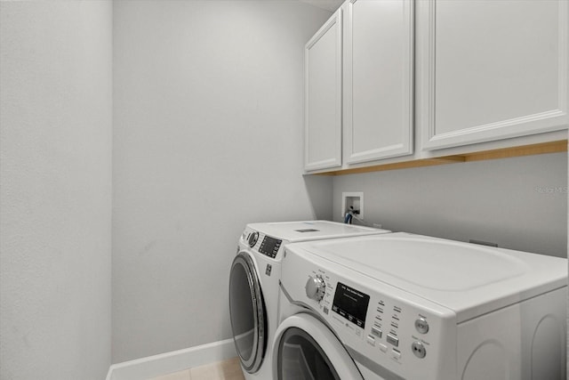 washroom featuring washer and dryer, cabinets, and light tile patterned floors