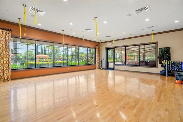 exercise area with light wood-type flooring, ornamental molding, and a wealth of natural light