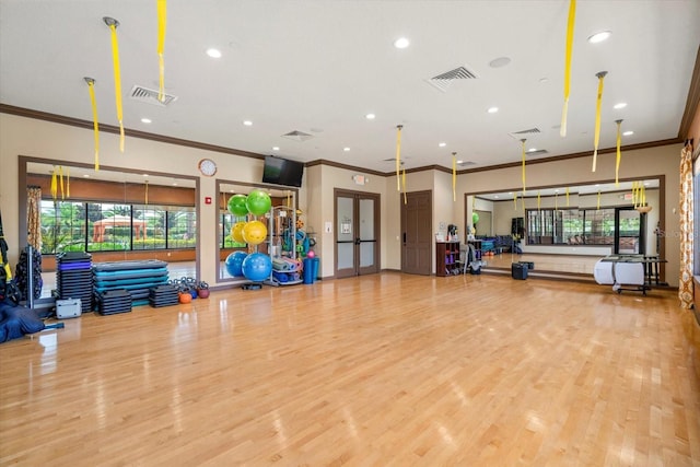 gym with light hardwood / wood-style floors and ornamental molding