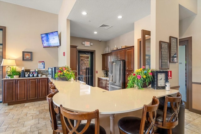 kitchen featuring a kitchen breakfast bar, kitchen peninsula, a textured ceiling, and high end refrigerator