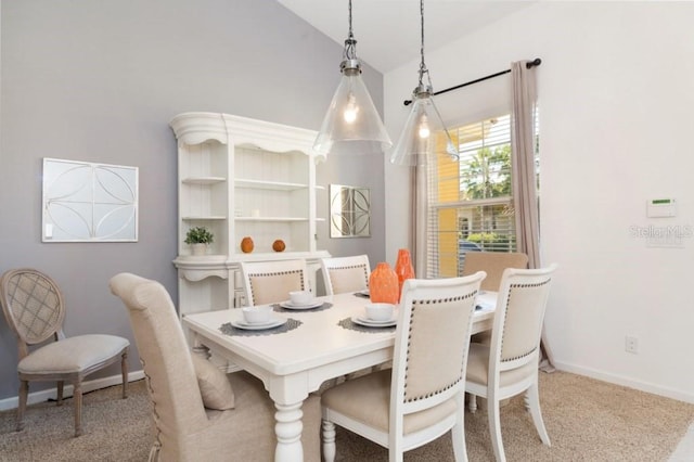 carpeted dining room with lofted ceiling