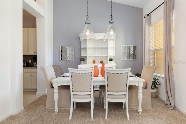 dining area featuring lofted ceiling and light colored carpet