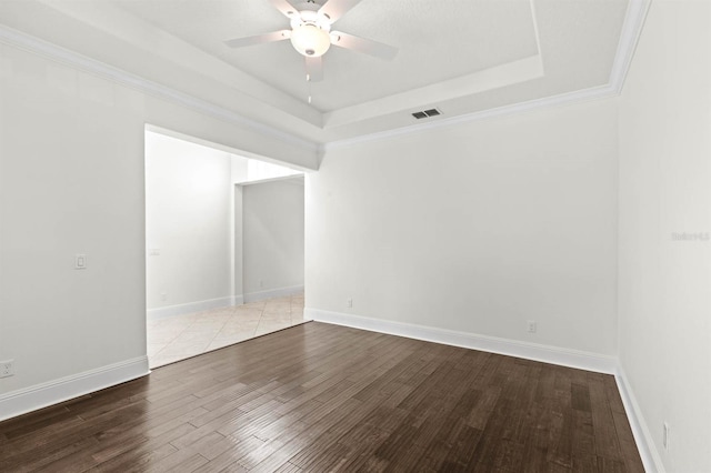 empty room featuring a raised ceiling, ornamental molding, ceiling fan, and hardwood / wood-style flooring