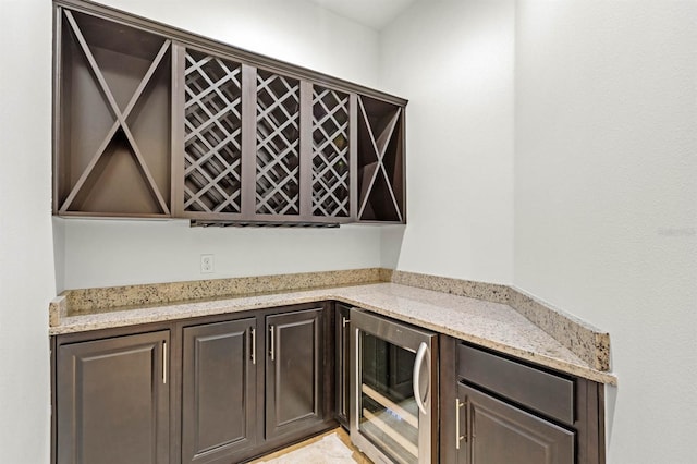 interior space featuring dark brown cabinets, beverage cooler, and light stone countertops