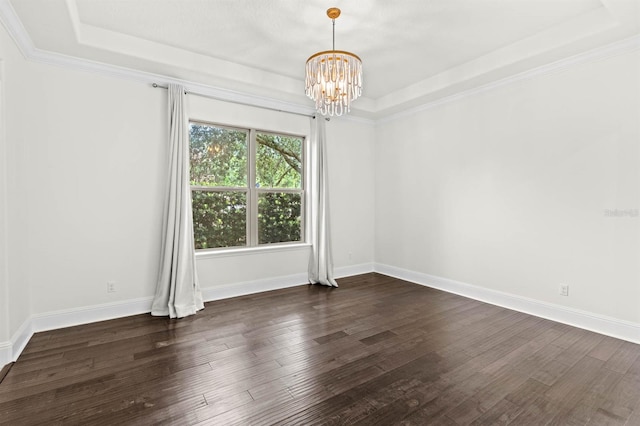 spare room with a raised ceiling, crown molding, dark hardwood / wood-style flooring, and a notable chandelier