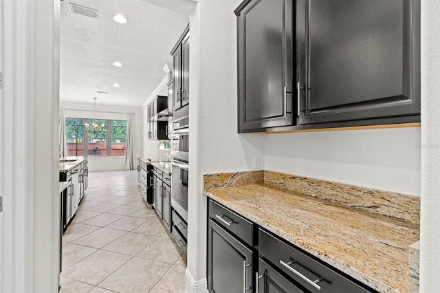 kitchen with hanging light fixtures, light stone counters, light tile patterned floors, a textured ceiling, and oven