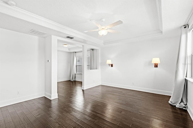 spare room featuring ceiling fan, a textured ceiling, a tray ceiling, dark hardwood / wood-style floors, and crown molding