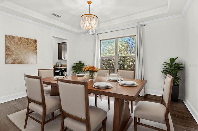 dining space featuring an inviting chandelier, a raised ceiling, ornamental molding, and dark hardwood / wood-style flooring