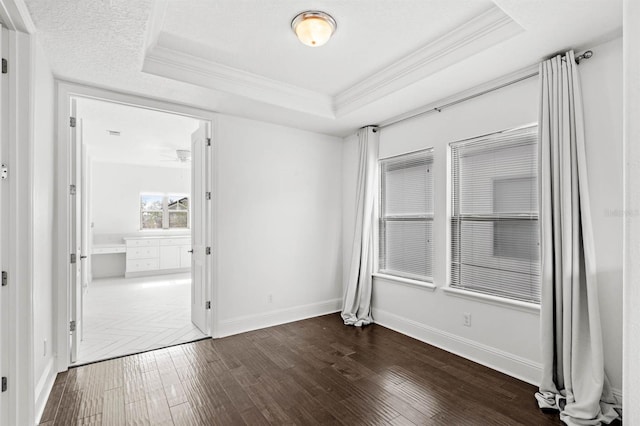 spare room featuring a tray ceiling, crown molding, and dark hardwood / wood-style flooring