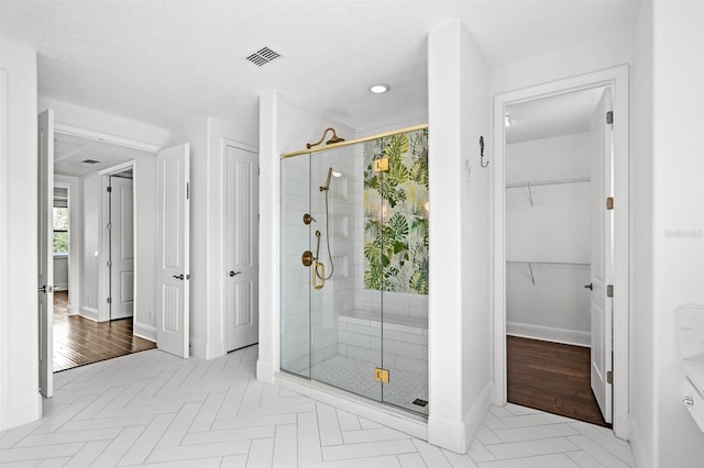 bathroom featuring wood-type flooring, a textured ceiling, and an enclosed shower