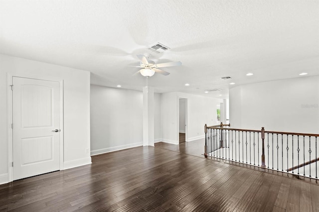 empty room with ceiling fan, dark hardwood / wood-style floors, and a textured ceiling