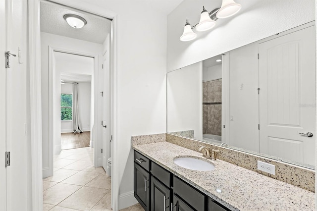 bathroom featuring tile patterned floors, a textured ceiling, vanity, and toilet