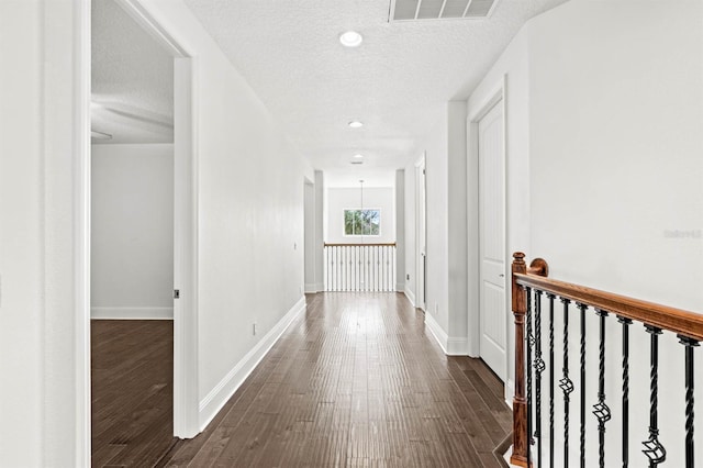 hallway featuring a textured ceiling and dark hardwood / wood-style flooring