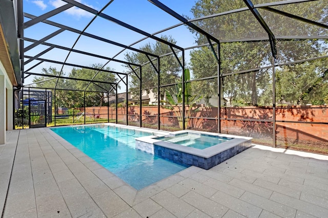 view of swimming pool featuring glass enclosure, an in ground hot tub, and a patio