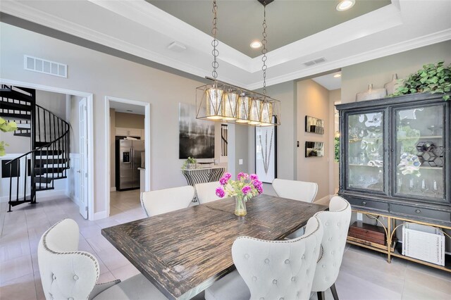 tiled dining space with a raised ceiling and ornamental molding