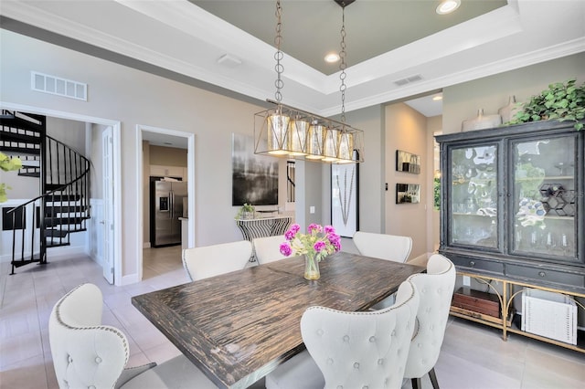 tiled dining space with ornamental molding and a raised ceiling