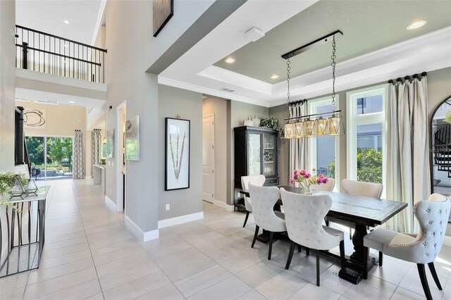 dining area with ornamental molding, a raised ceiling, and light tile patterned floors