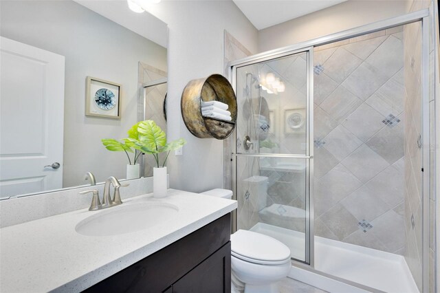 bathroom featuring vanity, an enclosed shower, and toilet