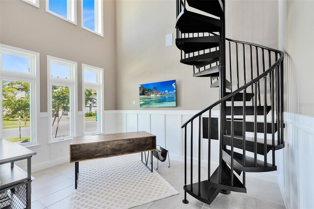 stairs with tile patterned flooring and a towering ceiling