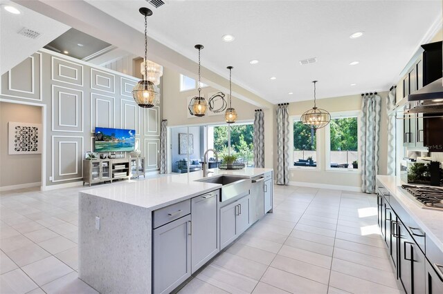 kitchen featuring light tile patterned flooring, pendant lighting, an island with sink, sink, and light stone countertops