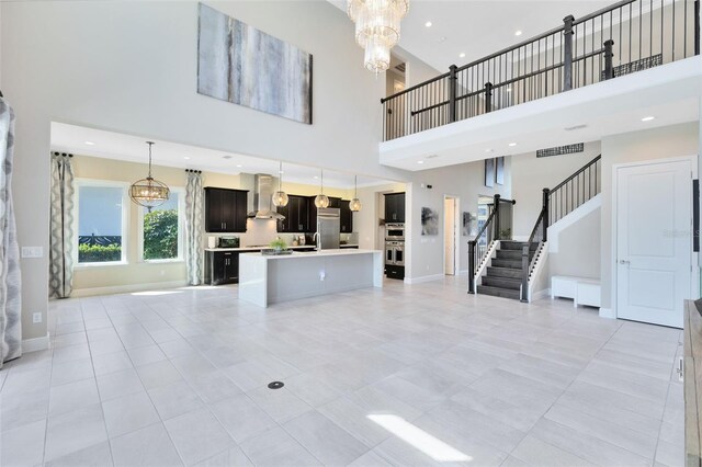 unfurnished living room featuring light tile patterned flooring, a towering ceiling, and a chandelier