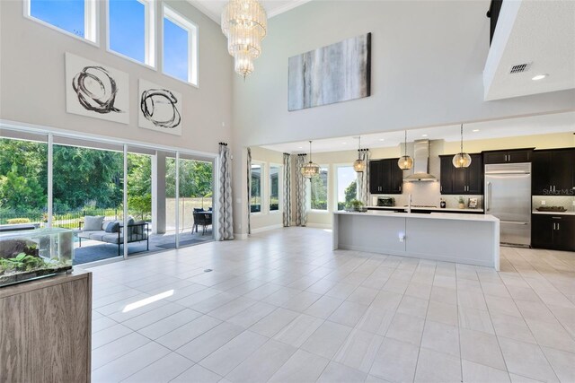 unfurnished living room with a towering ceiling, light tile patterned floors, and a notable chandelier