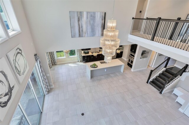 living room with an inviting chandelier, light tile patterned floors, and a high ceiling