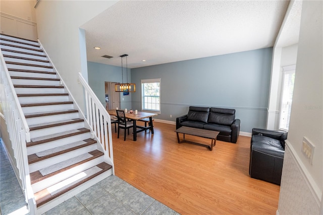 living room featuring a notable chandelier, a textured ceiling, and light hardwood / wood-style flooring