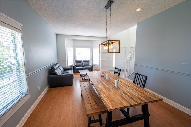 dining room featuring hardwood / wood-style floors, a textured ceiling, and a notable chandelier