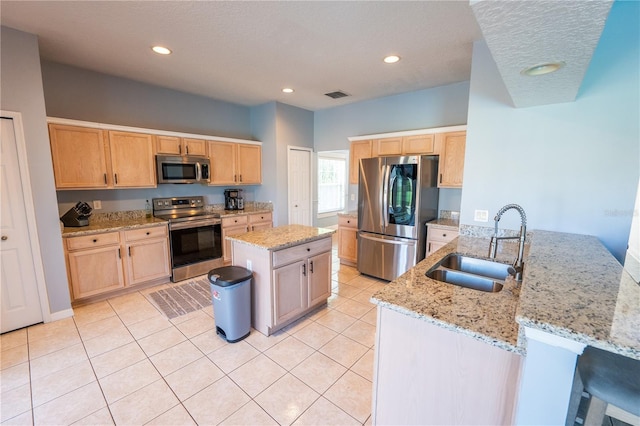 kitchen with light stone counters, sink, a kitchen island with sink, and appliances with stainless steel finishes