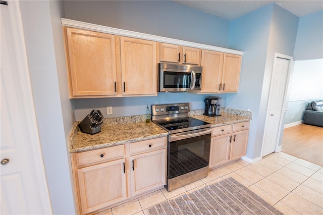 kitchen featuring light brown cabinets, light tile patterned floors, and stainless steel appliances