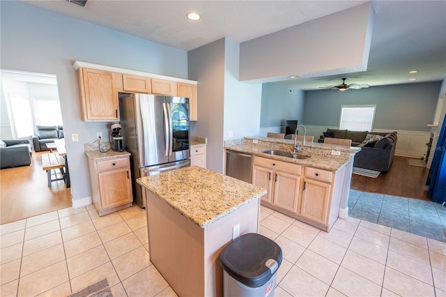 kitchen with appliances with stainless steel finishes, light brown cabinets, light tile patterned floors, and sink