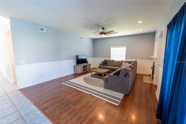 living room featuring ceiling fan, hardwood / wood-style floors, and a textured ceiling