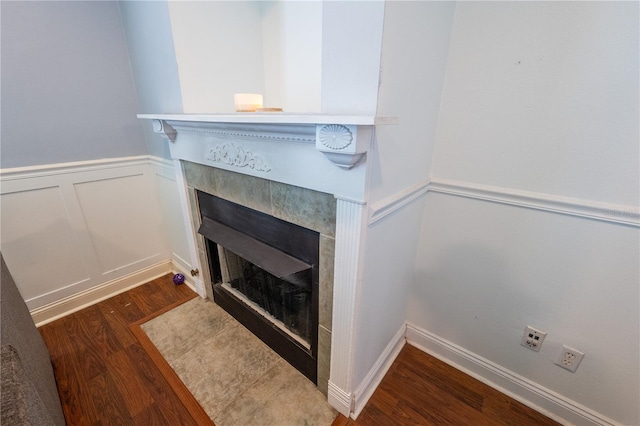 interior details featuring a tiled fireplace and wood-type flooring