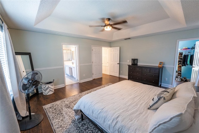 bedroom featuring ensuite bathroom, ceiling fan, a spacious closet, a tray ceiling, and a closet