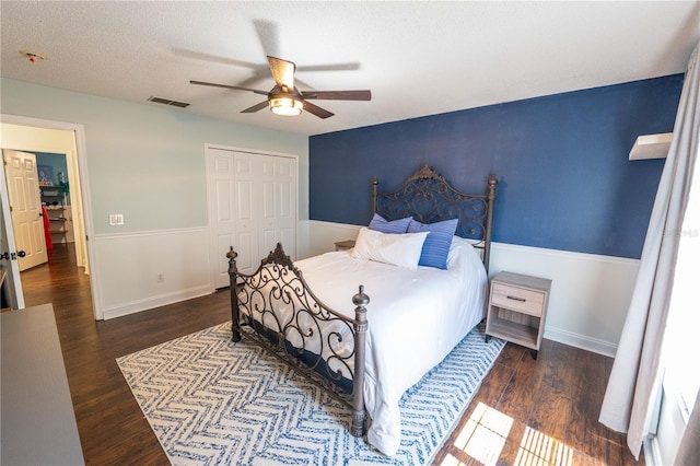 bedroom featuring dark hardwood / wood-style flooring, ceiling fan, a closet, and a textured ceiling